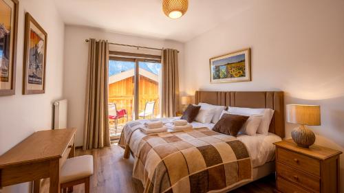 Un dormitorio con una cama y un escritorio y una ventana. en L'O Rouge - Apt A102 - BO Immobilier- Châtel- Reduced prices on ski passes Châtel & Portes du Soleil, en Châtel