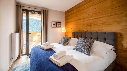 une chambre avec un grand lit avec un mur en bois dans l'établissement The View - Apt 05 - BO Immobilier - Châtel - Multipass 2025 offert, à Châtel