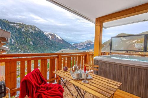 d'un balcon avec un bain à remous et une table en bois. dans l'établissement L'O Rouge - Apt A02 - BO Immobilier, à Châtel