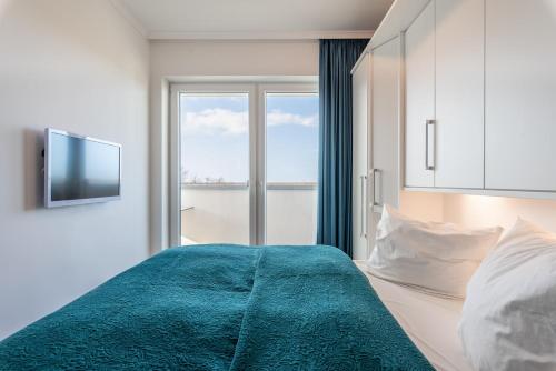 Schlafzimmer mit einem Bett, einem TV und einem Fenster in der Unterkunft Residenz Am Meer in Börgerende-Rethwisch