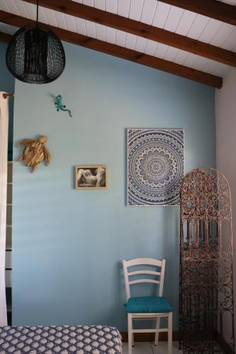 a bedroom with a blue wall with a chair and artwork at Villa Rosa Karibella in Saint-François
