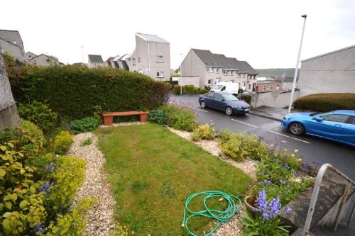 a garden with a bench and cars parked in a street at Strachan House in Inverkeithing