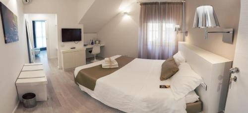 una camera da letto con un grande letto bianco e una televisione di Rigel Villanova Rooms a Cagliari