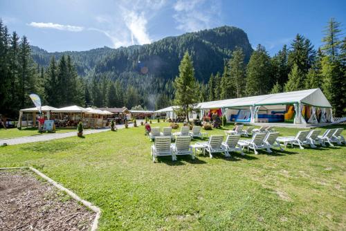 a group of chairs in a field with a tent at Hotel Dolomiti Schloss in Canazei