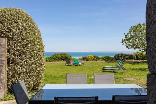a table and chairs in a field with the ocean at La Metairie-du-Vauhariot - Vue Mer et Mont Saint Michel - Piscine Chauffée - Accès GR34 in Cancale