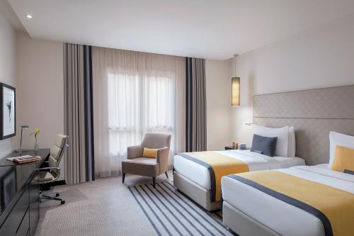 a hotel room with two beds and a chair at Voco - Riyadh by IHG in Riyadh