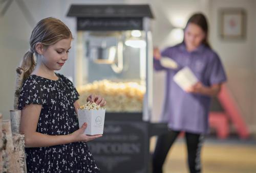 a little girl is holding popcorn in a box at Lisi Family Hotel in Reith bei Kitzbühel