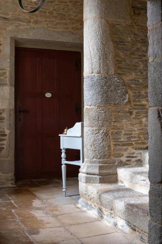 a stone building with a red door and a white table at La Metairie-du-Vauhariot - Vue Mer et Mont Saint Michel - Piscine Chauffée - Accès GR34 in Cancale