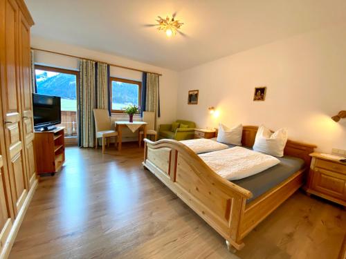 a bedroom with a large bed and a living room at Lechnerhof Hotel-Garni in Achenkirch