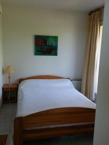 une chambre avec un lit et un tableau au mur dans l'établissement Appartement(4-6 pers) Superbe vue mer, Rés. Les RIVES DE LA FAVIERE, à Bormes-les-Mimosas