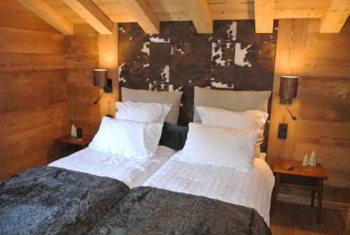 two twin beds in a room with wooden walls at Chalet Teleporte in Les Gets