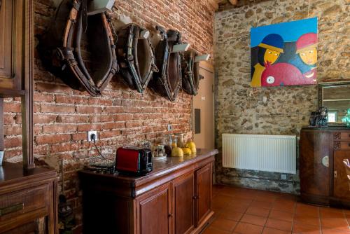 a kitchen with a brick wall and a counter with baseball bats at Domaine du Mas Bazan in Alénya