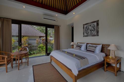 een slaapkamer met een bed, een tafel en een raam bij Kaja Villa in Ubud