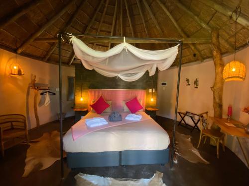 a bedroom with a canopy bed with pink pillows at Addo African Home in Addo