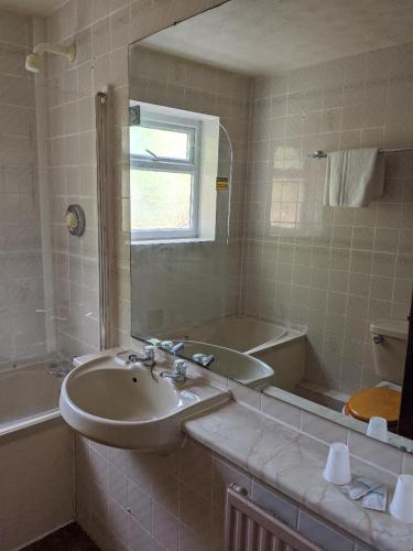 a bathroom with a sink and a tub and a mirror at Balmoral Lodge Hotel in Southport
