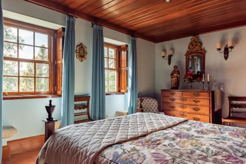 a bedroom with a bed and a dresser and windows at Quinta de Mourães Casa dos Rododendros in Lever