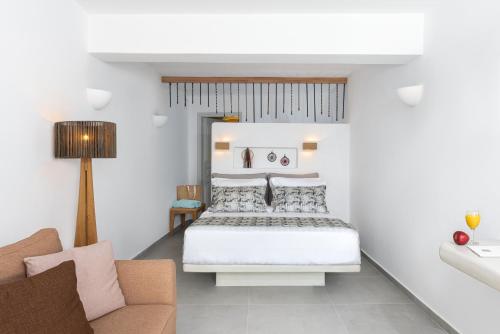 a white bedroom with a bed and a couch at Adamant Suites in Fira