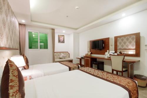 a hotel room with two beds and a desk at Paris Luxury Hotel & Apartment Nha Trang in Nha Trang