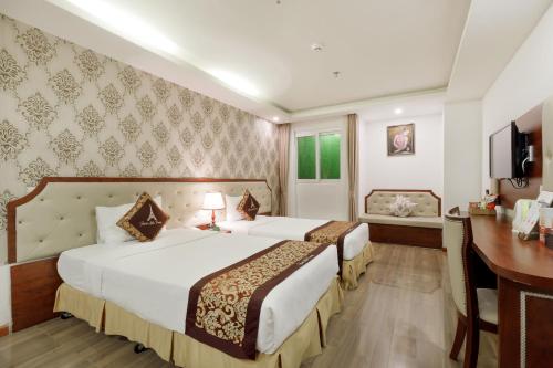 a hotel room with two beds and a desk at Paris Luxury Hotel & Apartment Nha Trang in Nha Trang