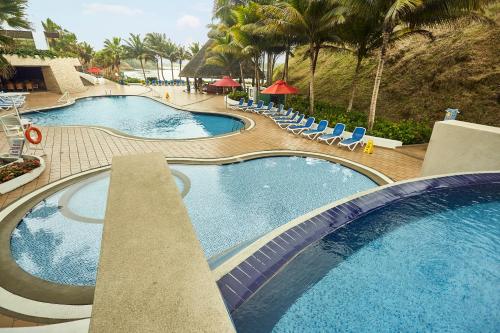 una vista aérea de 2 piscinas con sillas y palmeras en Royal Decameron Mompiche - All Inclusive, en Mompiche
