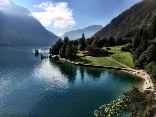 a view of a lake with a house on the shore at Lechnerhof Hotel-Garni in Achenkirch