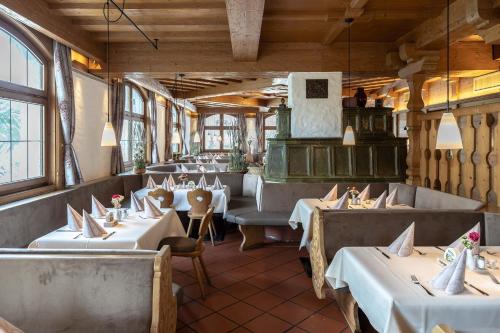 un restaurante con mesas y sillas blancas y ventanas en Alter Hof, en Vaterstetten