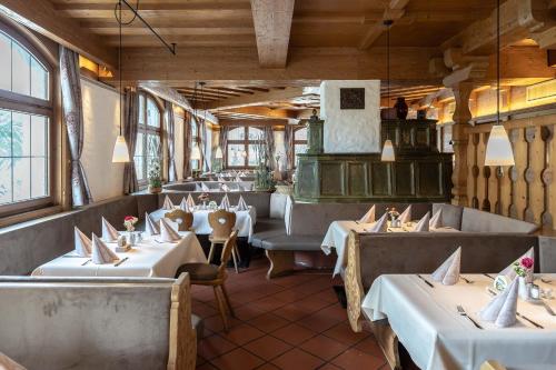 ein Restaurant mit weißen Tischen, Stühlen und Fenstern in der Unterkunft Alter Hof in Vaterstetten