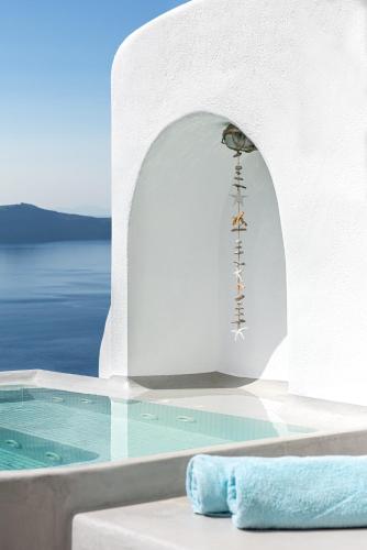 a swimming pool with a sign on a white wall at Adamant Suites in Fira