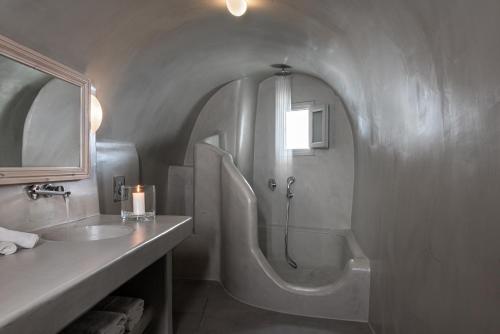 a bathroom with a shower and a sink and a tub at Adamant Suites in Fira