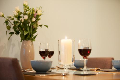 a table with two glasses of wine and a candle at Glenwood Apartment at The Highland Club in Fort Augustus