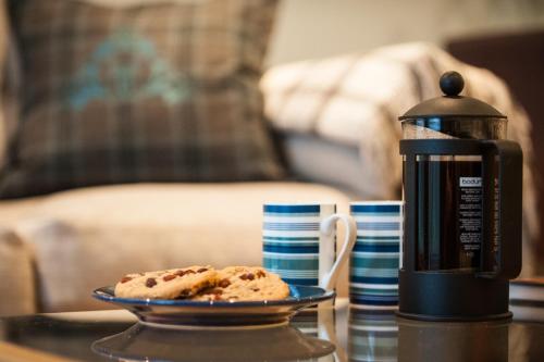 a plate of food on a table next to a coffee maker at Glenwood Apartment at The Highland Club in Fort Augustus