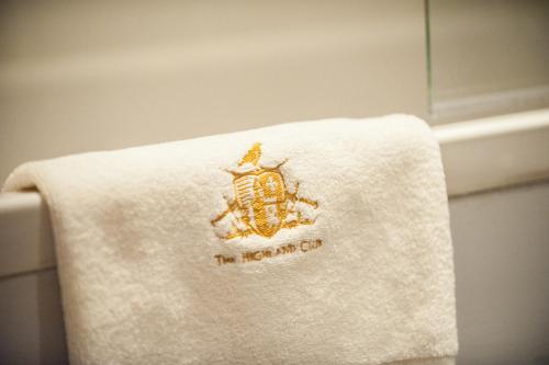 a towel with the hogan on it sitting on a toilet at Glenwood Apartment at The Highland Club in Fort Augustus