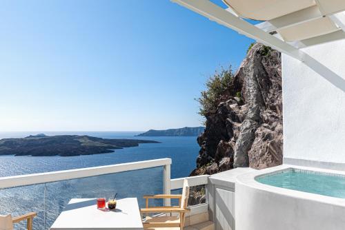a balcony with a swimming pool and the ocean at Adamant Suites in Fira