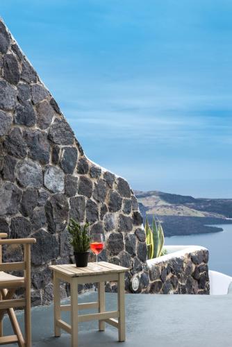 a table with a glass of wine and a chair at Adamant Suites in Fira