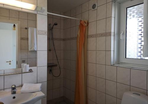 ヒアツハルスにあるMunchs Badehotelのバスルーム(オレンジ色のシャワーカーテン、シンク付)
