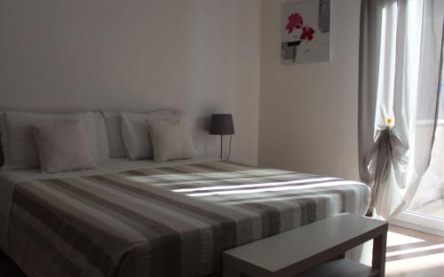 a white bedroom with a bed and a window at Hotel La Ruota Dei Pavoni in Osimo