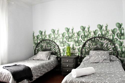 a bedroom with two beds and a wall covered in plants at Aloja Ayamonte in Ayamonte