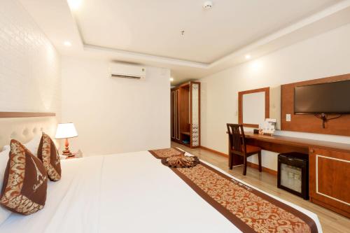 a bedroom with a bed and a desk with a television at Paris Luxury Hotel & Apartment Nha Trang in Nha Trang