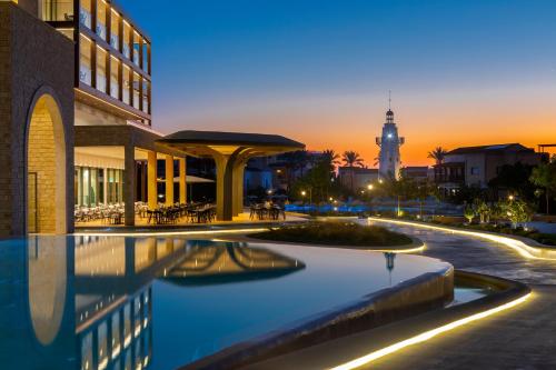 a hotel swimming pool with a clock tower in the background at Aliathon Ionian in Paphos City