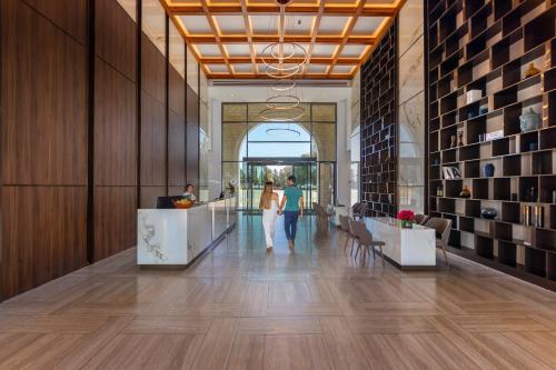a lobby with a woman walking down a hallway at Aliathon Ionian in Paphos City