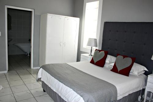a bedroom with a large bed with two red pillows at Karoopark Guest House in Graaff-Reinet