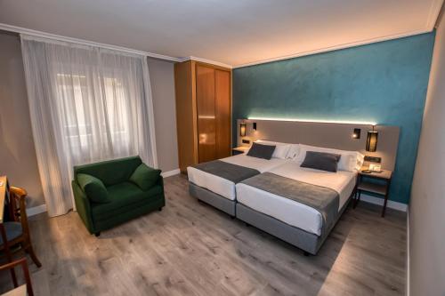 Habitación de hotel con cama y silla verde en Hotel Castilla Vieja en Palencia