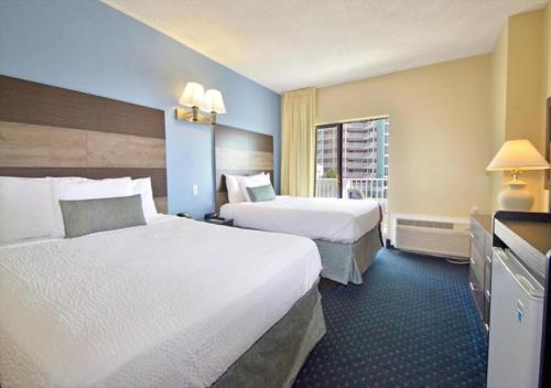 een hotelkamer met 2 bedden en een raam bij Coastal Palms Inn and Suites in Ocean City