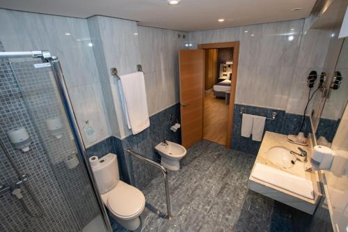 a bathroom with two toilets and a shower and a sink at Hotel Castilla Vieja in Palencia