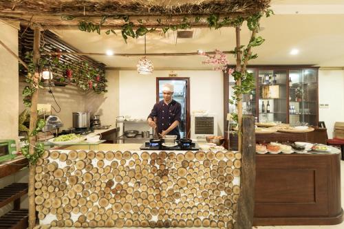 a man standing behind a counter in a kitchen at Paris Nha Trang Hotel in Nha Trang