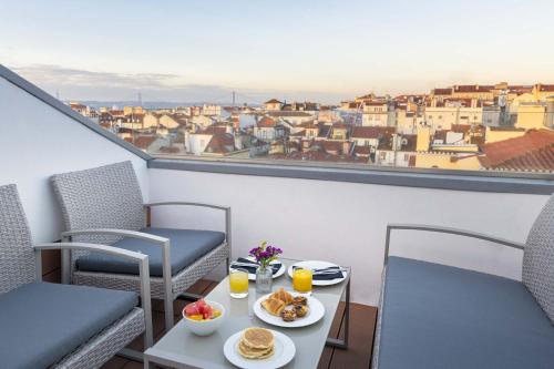 a table with plates of food and drinks on a balcony at 9Hotel Mercy in Lisbon