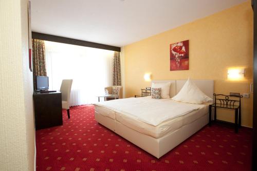 ein Schlafzimmer mit einem großen weißen Bett und einem roten Teppich in der Unterkunft Hotel Klinkner in Emmelshausen
