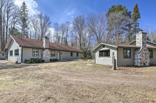 a house with a stone chimney on a yard at Waterfront Pike Lake Retreat Snowmobile Paradise in Park Falls