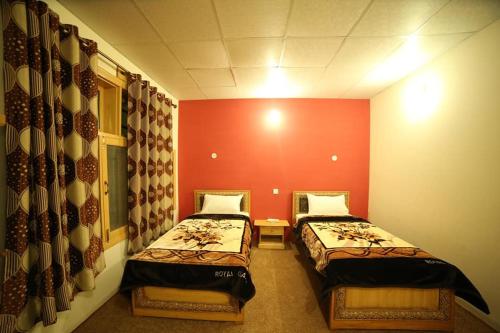 two beds in a room with red walls at Eden Lake View Hotel in Baltit