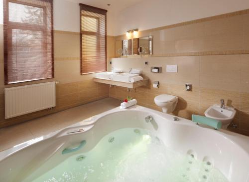 a bathroom with a tub and a toilet and a sink at Spa Resort PAWLIK-AQUAFORUM in Františkovy Lázně